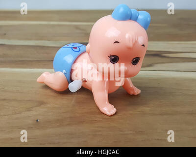 Mechanical wind up crawling baby toy on wood background Stock Photo