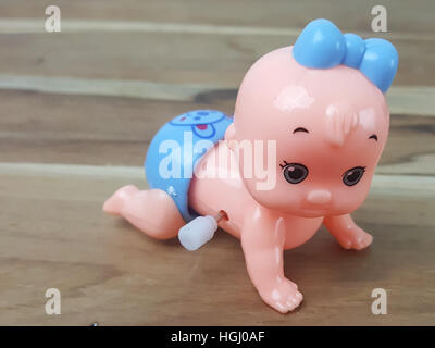 Mechanical wind up crawling baby toy on wood background Stock Photo