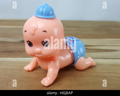 Mechanical wind up crawling baby toy on wood background Stock Photo