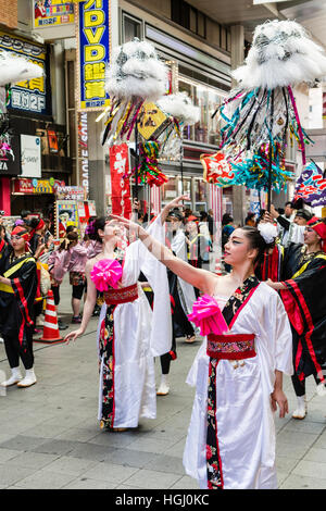 Japanese Dance Festival. Women team performing historical dance in shopping mall. Dancers in white robes with standard bearers behind. Stock Photo