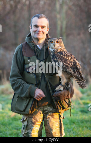 A falconer in the countryside with his bird of prey, a Eurasian Eagle Owl. UK. Stock Photo