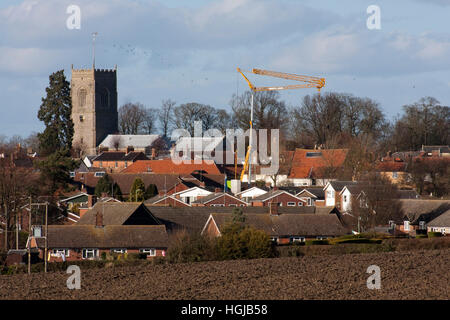 Construction crane poking up along with a church tower from Suffolk market town Framlingham Stock Photo