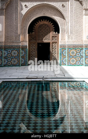 Arch and door reflected on pool, Ali ben Youssef Medersa (Koranic school), Marrakech, Morocco Stock Photo