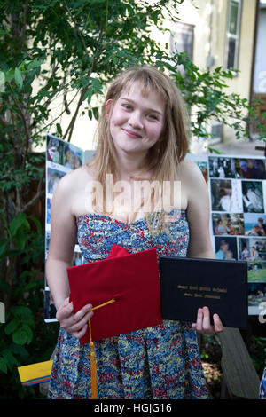 Happy teen woman, a recent high school graduate holding her diploma & red cap at her graduation party. St Paul Minnesota MN USA Stock Photo