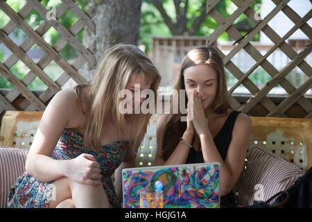 High school teen girls enjoying a computer internet page at an outdoor garden party. St Paul Minnesota MN USA Stock Photo