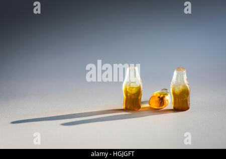 Group of three soft candy / jelly beans in the shape of bottles. Looks like group of three people. Middle bottle is toppled over Stock Photo