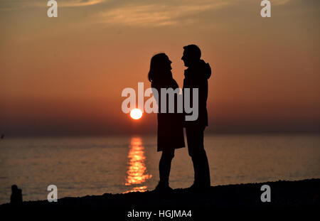 Brighton Sussex, UK. 22nd Jan, 2017. A couple enjoy a romantic moment on Brighton beach as the sun sets behind them at dusk after a cold but beautiful day on the south coast Credit: Simon Dack/Alamy Live News Stock Photo