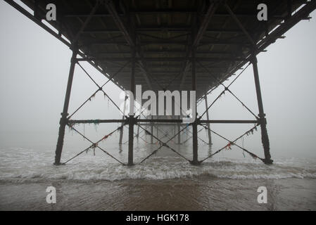 Under Worthing Pier on a foggy day at low tide in Worthing, West Sussex, England. Stock Photo