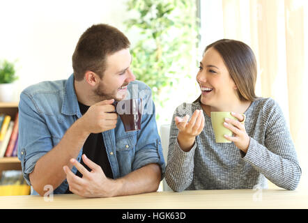Front view of a casual couple talking looking each other during breakfast in a table of the living room at home Stock Photo