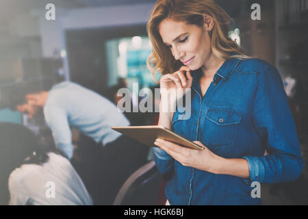 Beautiful blond businesswoman holding tablet in modern office Stock Photo