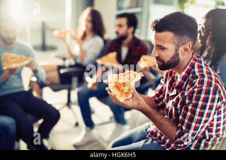 Coworkers eating pizza during work  break at office Stock Photo