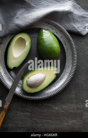 Avocado in the metal plate on the dark scratched table Stock Photo