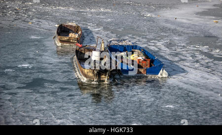 Danube, Serbia - Three anchored fishing boats trapped in a frozen river Stock Photo