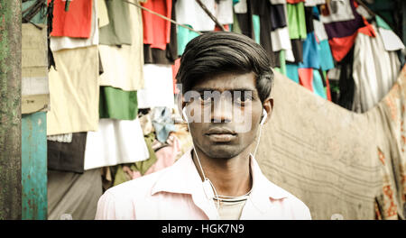 Modern young Indian man in Kolkata market with white headphones. Stock Photo