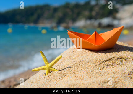 Paper boat and starfish in the sand at the beach Stock Photo