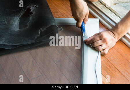 Hands of person removed the old door screen and fitting the new one Stock Photo