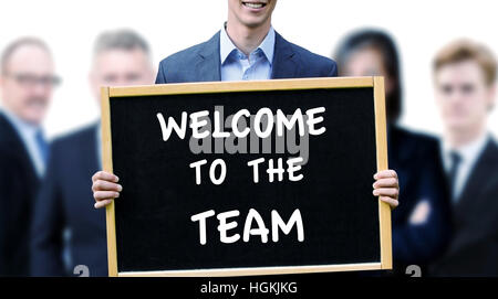 young businessman holding a sign with the words Welcome To The Team and group of people behind him Stock Photo