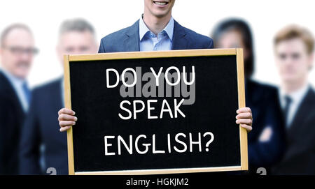 young businessman holding a sign with the words Do You Speak English and group of people behind him Stock Photo