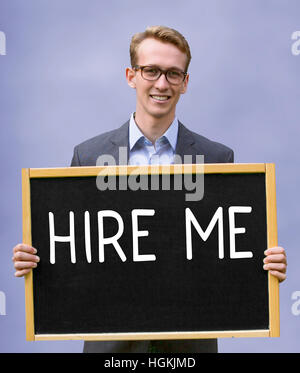 young businessman holding chalkboard with the words Hire Me Stock Photo