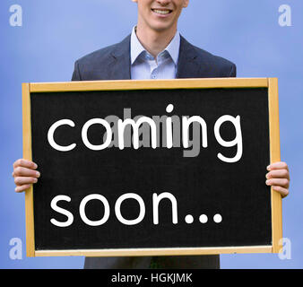 young businessman holding chalkboard with the words Coming Soon Stock Photo