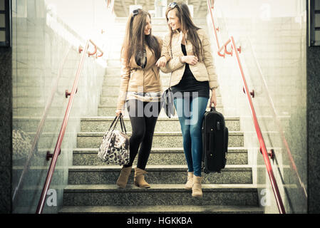 Two female friends at railroad station, coming down from stair Stock Photo