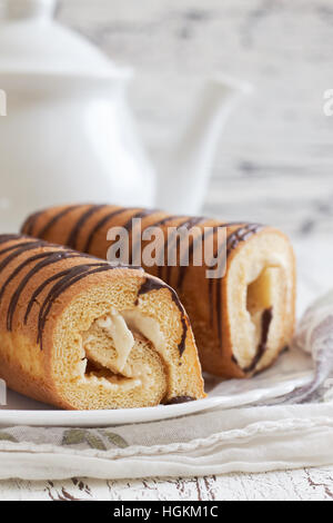 Sweet swiss rolls (roulade) with white cream served on white plate. Copy space Stock Photo