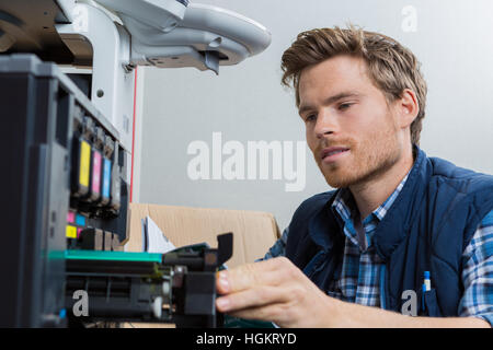 young male technician is repairing a printer at office Stock Photo