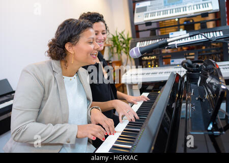 Women playing duet on piano and singing Stock Photo