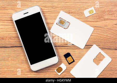 Smartphone with blank screen and SIM cards on the table, top view Stock Photo