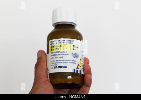 Hand Holding Cefalexin Sandoz antibiotic isolated against white background Stock Photo