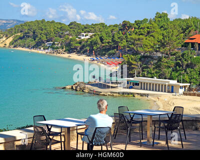 Man sat at seafront restaurant overlooking the beaches of Platis Gialos towards lassi, Kefalonia Island, Greece. Stock Photo