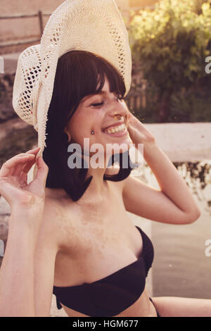 Young happy woman smiling and wearing a black bikini in a natural pool at summer