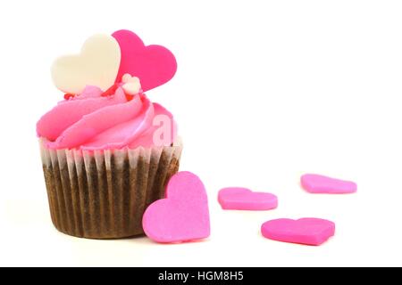 Chocolate Valentines Day cupcake with pink frosting and hearts over a white background