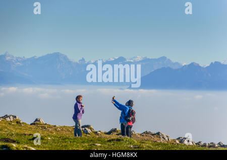 Hikers taking a selfie in front of a panorama of the Swiss Alps seen from the Dent de Vaulion in the Jura Stock Photo