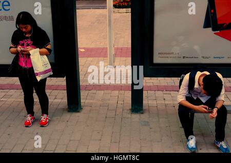 Guangzhou, Guangzhou, China. 11th Jan, 2017. Guangzhou, CHINA-January 11 2017: (EDITORIAL USE ONLY. CHINA OUT) .People use smartphones at a bus stop in Guangzhou, capital of south China's Guangdong Province, January 11th, 2017. Nowadays people become more addicted to mobile phones.Many people overuse smartphones in their daily life. © SIPA Asia/ZUMA Wire/Alamy Live News Stock Photo