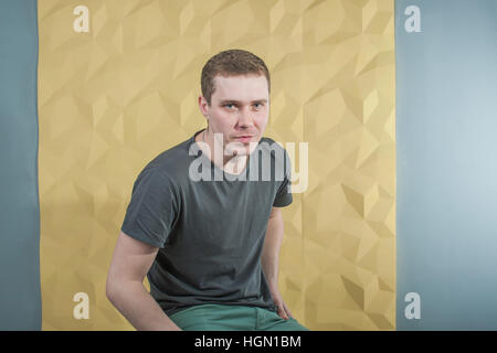 studio photography young brutal guy, on yellow background 3D volumetric wall Stock Photo