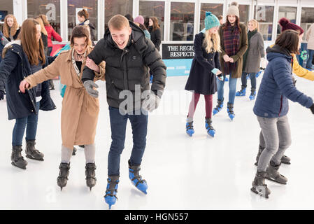 Young people enjoy the temporary ice skating rink at the Cambridge Christmas fair Parkers Piece Cambridge UK Stock Photo
