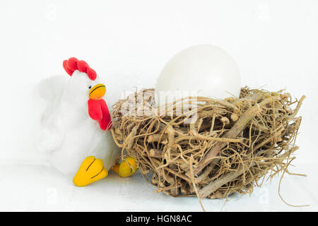 White stuffed chicken and wooden nest with big, huge egg inside in isolated white background. Stock Photo