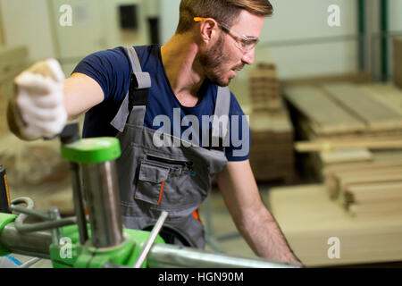Young man works in a factory for the production of furniture Stock Photo