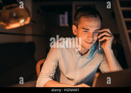 Smiling young businessman hard at work late in the evening Stock Photo