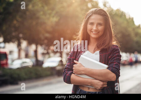 Smiling young woman with her digital tablet in the city Stock Photo