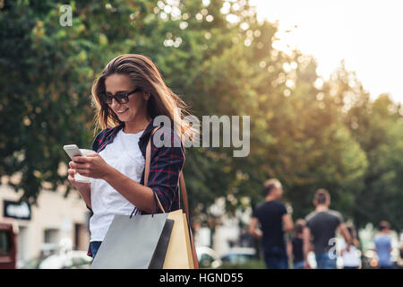 Young woman texting while enjoying a day shopping Stock Photo