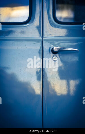 Closeup of locked blue oldtimer car back door with windows, lock and door handle in mysterious vintage light with reflections Stock Photo