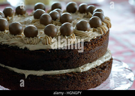 Chocolate cake in two layers with cream filling and topping decorated with Malteser chocolate balls. Stock Photo