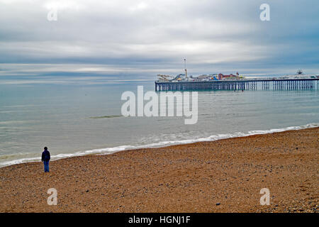 A lone figure on the beach looking at Brighton Pier on a winter's day Stock Photo