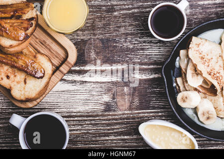 Homemade crepes with bananas and  cream caramel sauce in cast iron pan, sandwiches with caramel bananas, moms day or valentines day weekend brunch Stock Photo