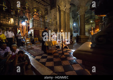 Jerusalem, Israel - July 13, 2014: Greek Orthodox priest holds mass in front of the Aedicula, place believed to be the tomb of Christ. Stock Photo