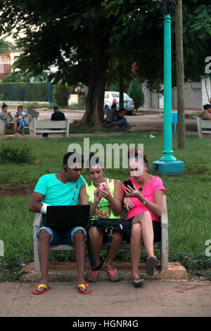Havana, Cuba. Cuban people using mobile telephone, cell phone, smartphone and ipad tablet for wi-fi internet in a Miramar park Stock Photo