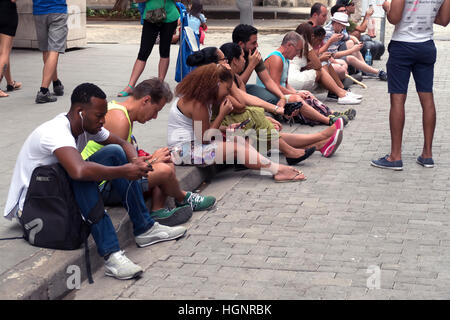 Havana, Cuba. Cuban people using mobile telephones, cell phones, smartphones for wi-fi internet in Calle Obispo, Habana Vieja Stock Photo