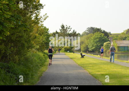 Runners and walkers exercising on the Bude canal, Bude, Cornwall Stock Photo